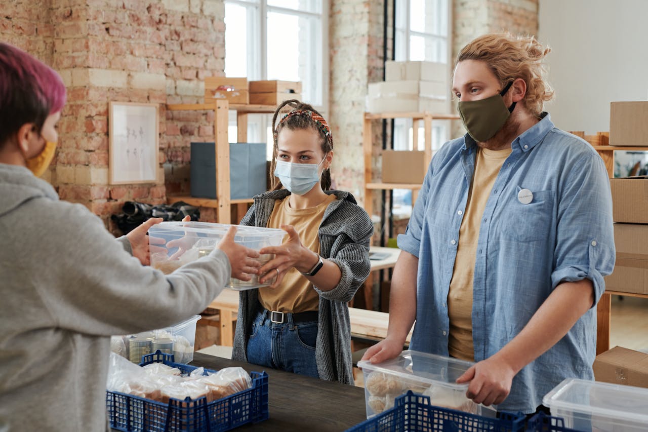 Volunteers wearing masks distribute food in a donation center, focusing on charity and community support.